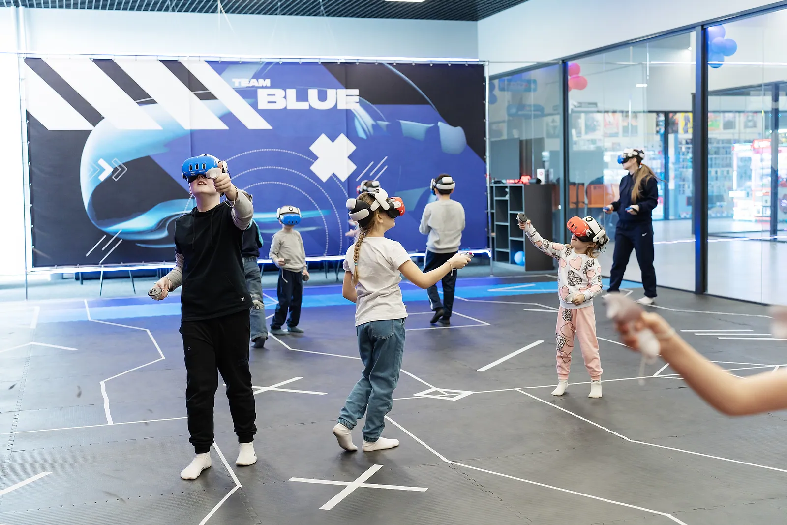 Дети в VR-шлемах играют в зале с баннером Team Blue